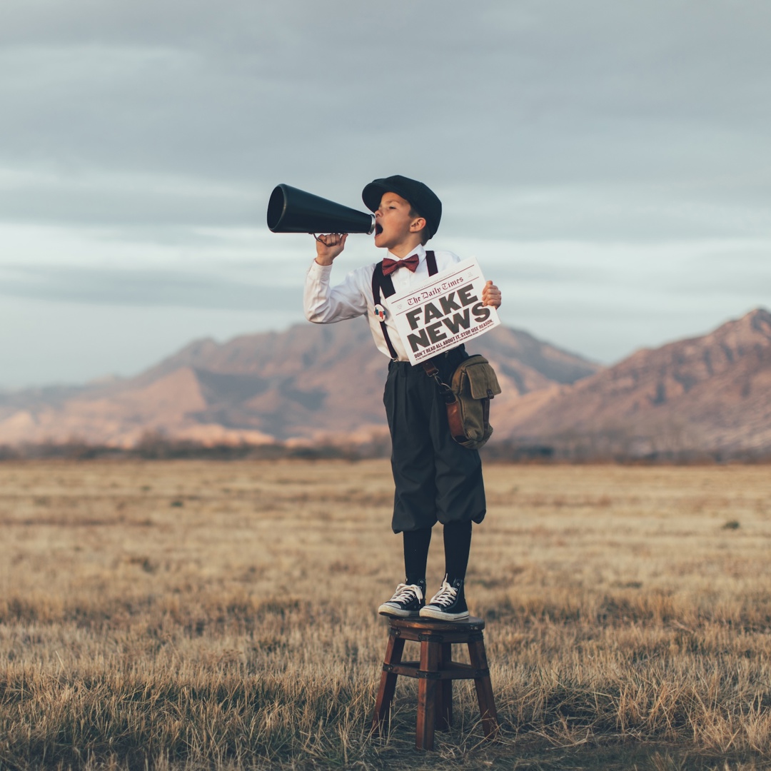 Jongen met megafoon op stoel over Fake News